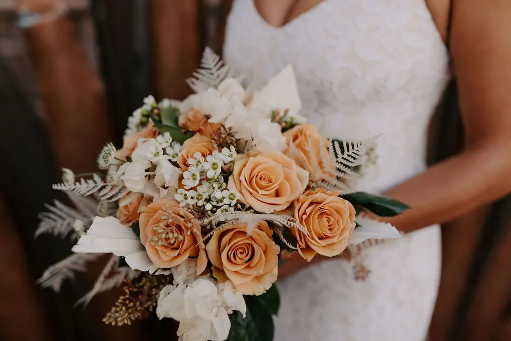 A bride holding her bouquet of flowers in front of the camera.