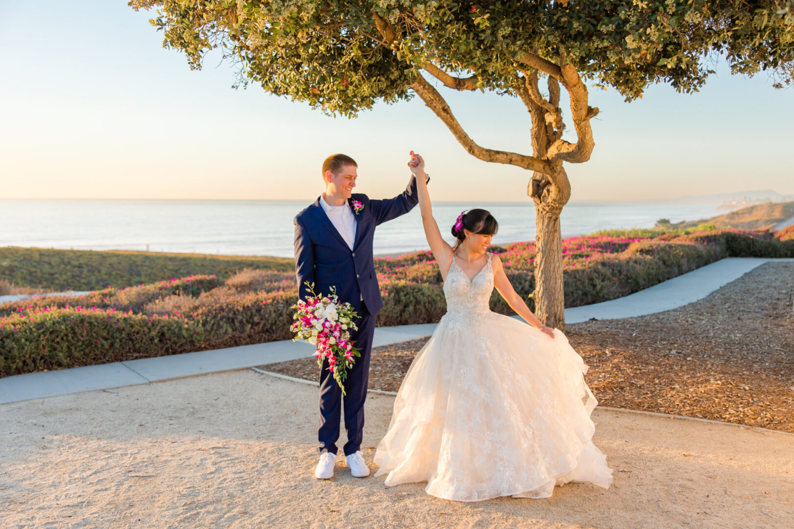 A man and woman holding hands under a tree.