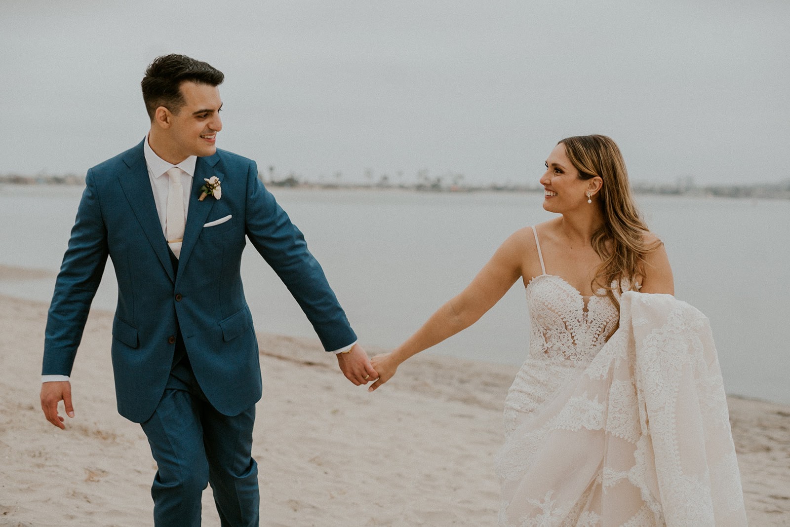 A man and woman holding hands on the beach.