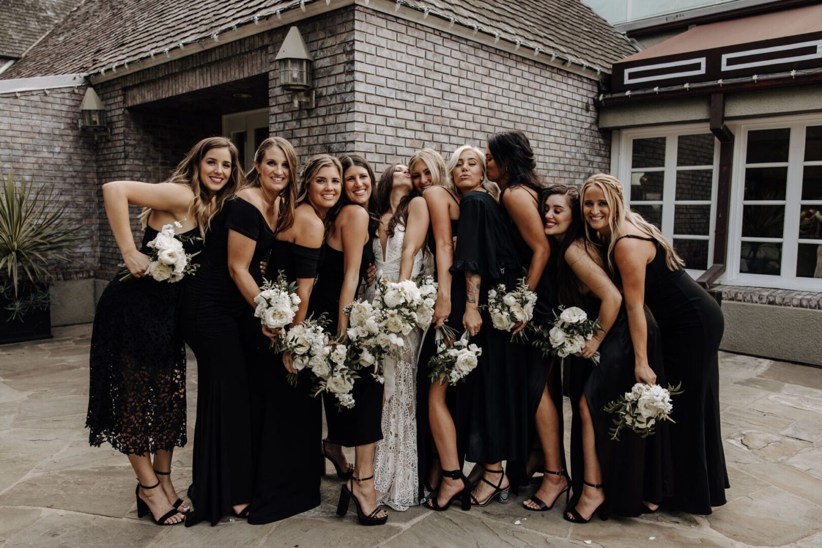 A group of women in black dresses holding white flowers.