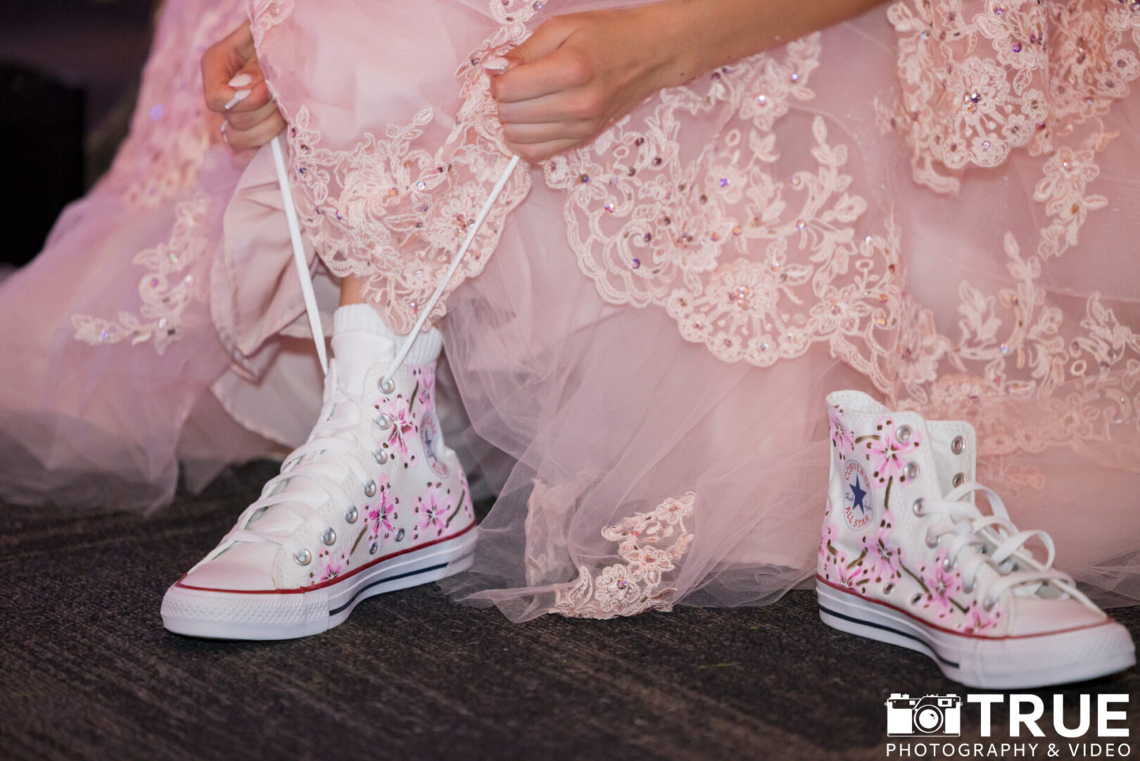 A woman in pink dress tying her shoe.