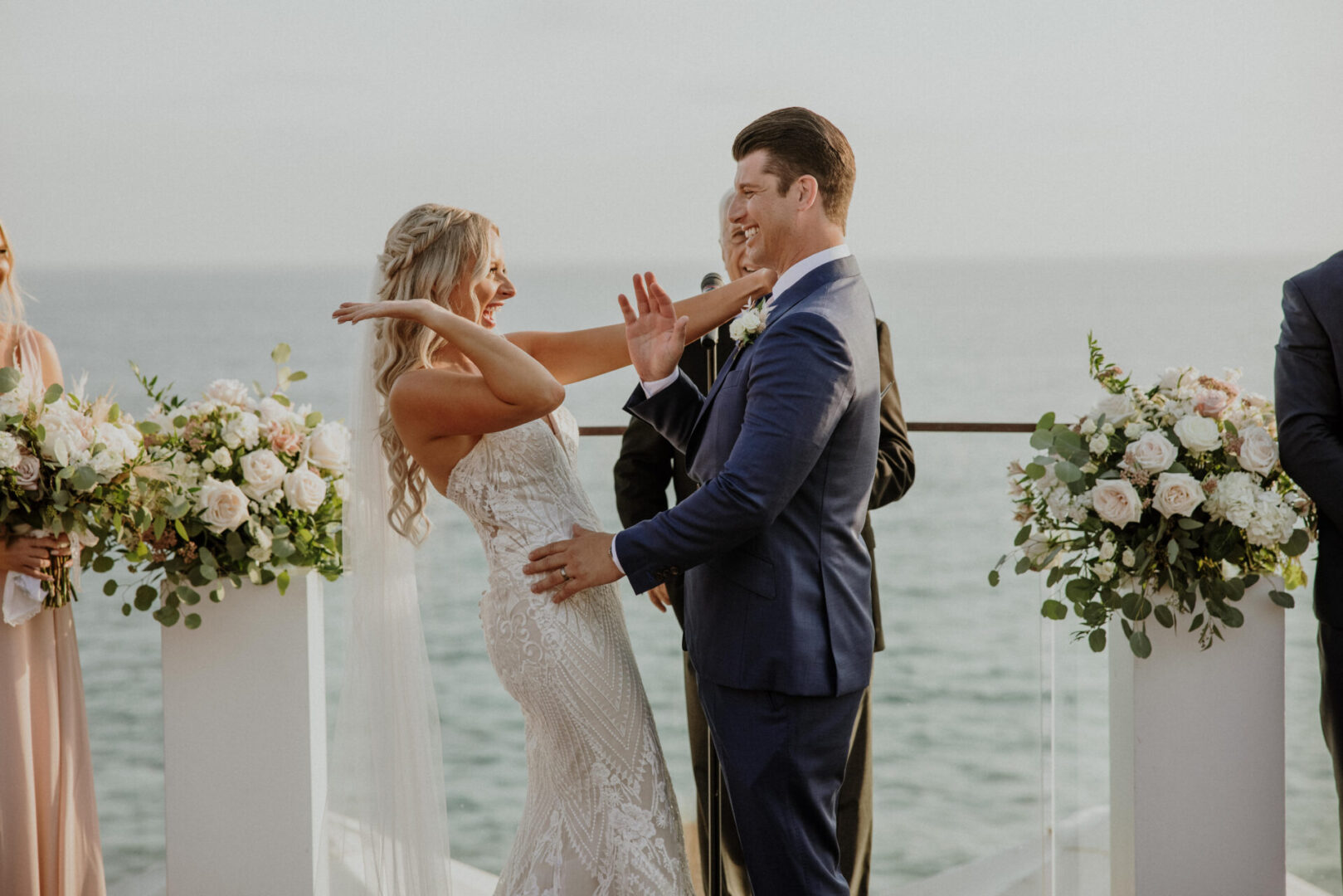 A bride and groom are holding hands on the deck of their wedding.