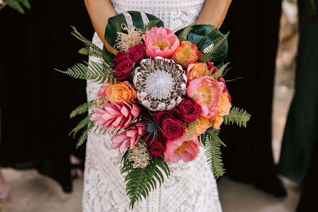 A bride holding her bouquet of flowers in front of the camera.