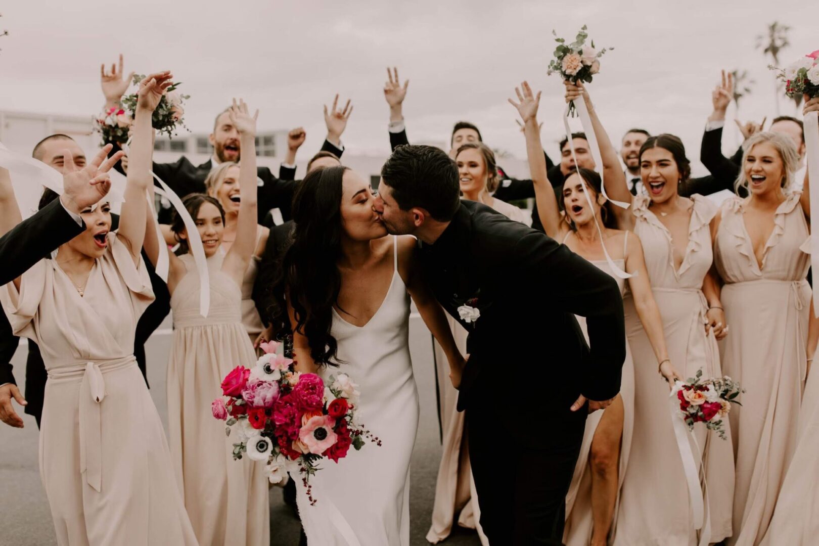 A bride and groom kissing in front of a crowd.