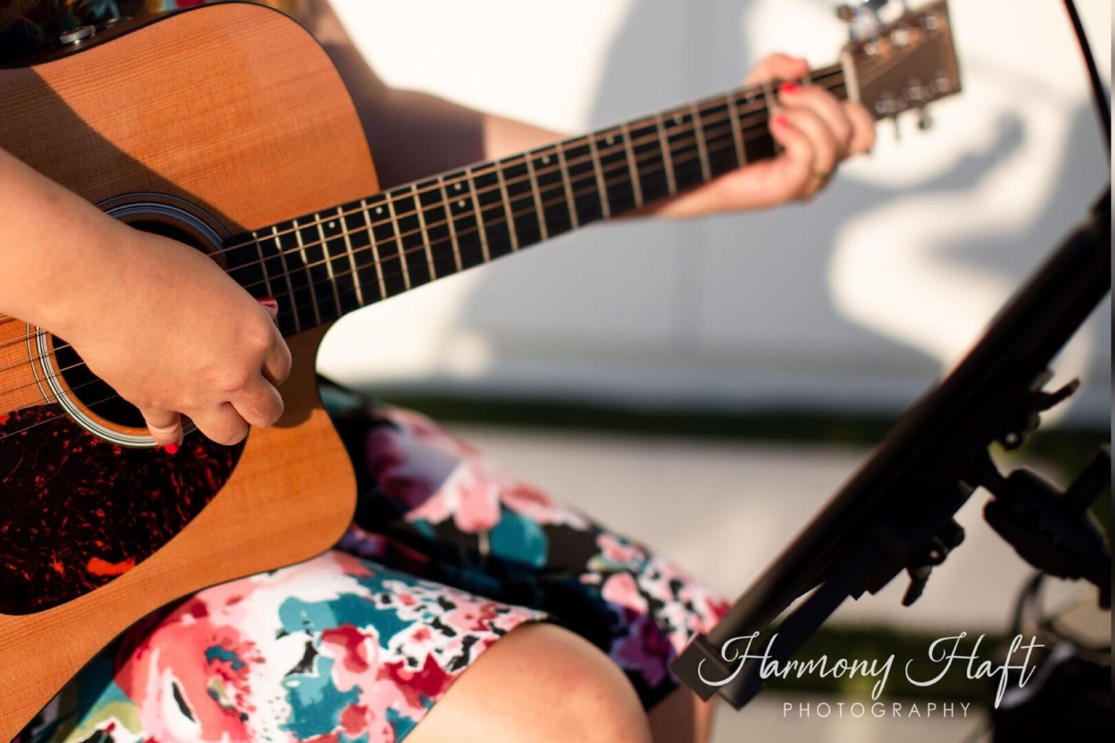 A person playing an acoustic guitar in the sunlight.