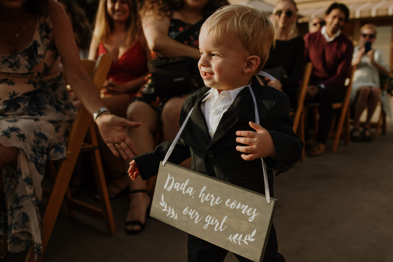 A young boy holding up a sign that says " dada bebe candy, am very girl neck ".